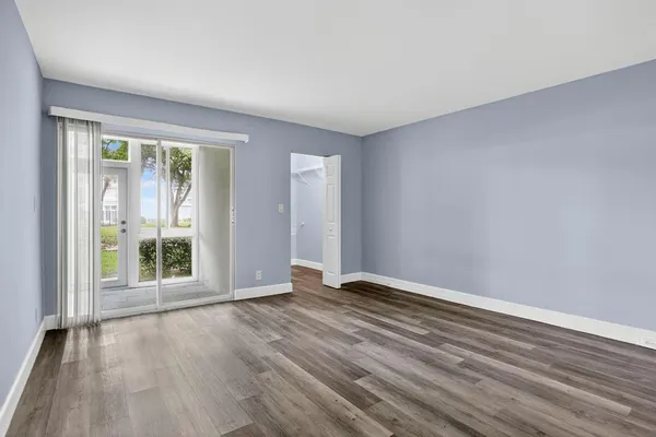 a view of an empty room with wooden floor and a window