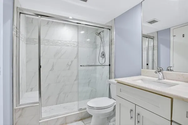 a bathroom with a granite countertop sink toilet and shower
