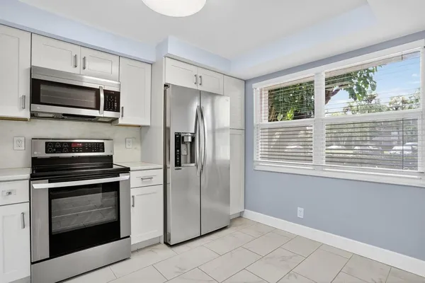 a kitchen with white cabinets stainless steel appliances and a window