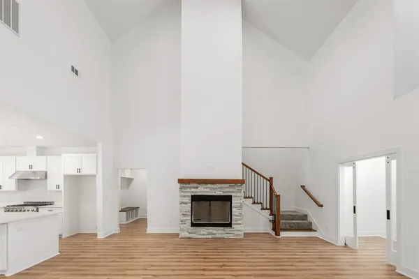 a kitchen with stainless steel appliances a white stove top oven a sink dishwasher and a refrigerator with wooden floor