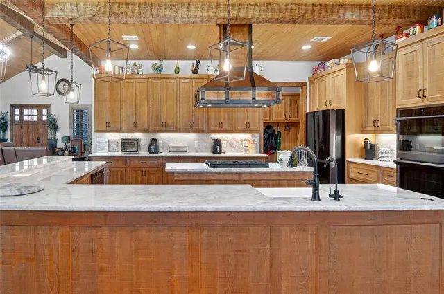 a kitchen with kitchen island granite countertop a sink a counter top space cabinets and stainless steel appliances