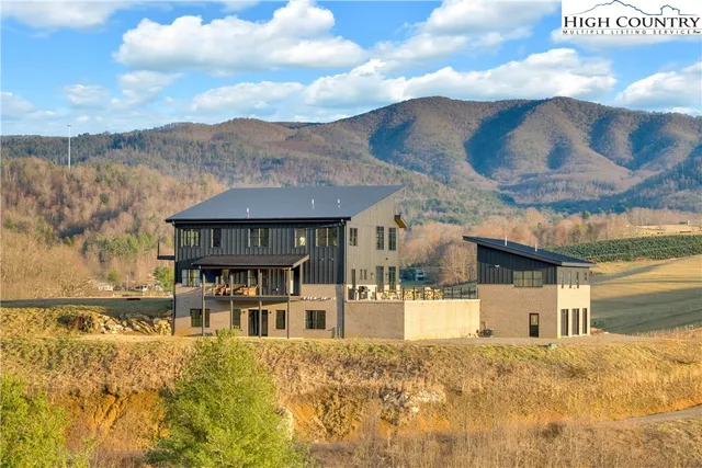 a view of a white house with a big yard and large tree