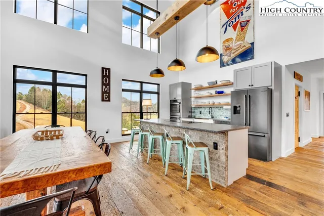 a kitchen with stainless steel appliances granite countertop a table chairs in it and wooden floors
