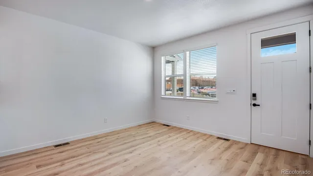an empty room with wooden floor and windows