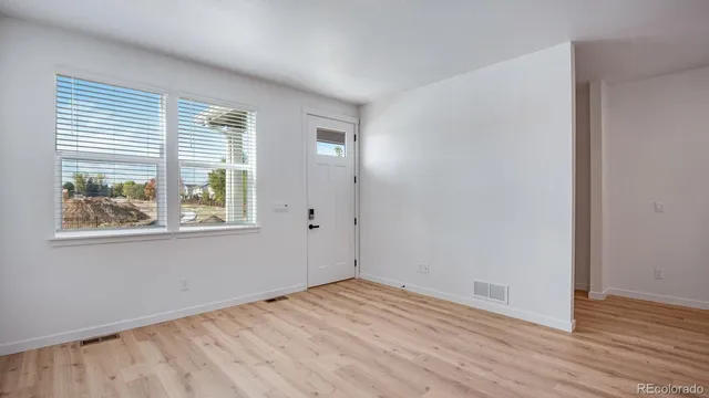 an empty room with wooden floor and windows