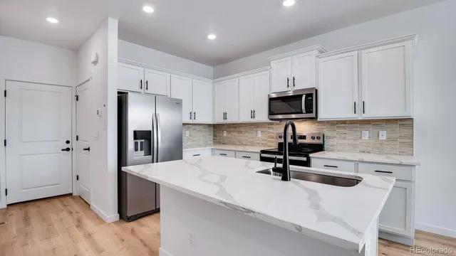 a kitchen with stainless steel appliances a refrigerator a stove a microwave and white cabinets