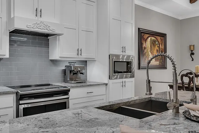 a kitchen with granite countertop a stove and white cabinets