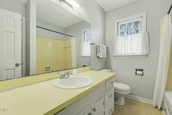 a bathroom with a granite countertop sink toilet and a mirror