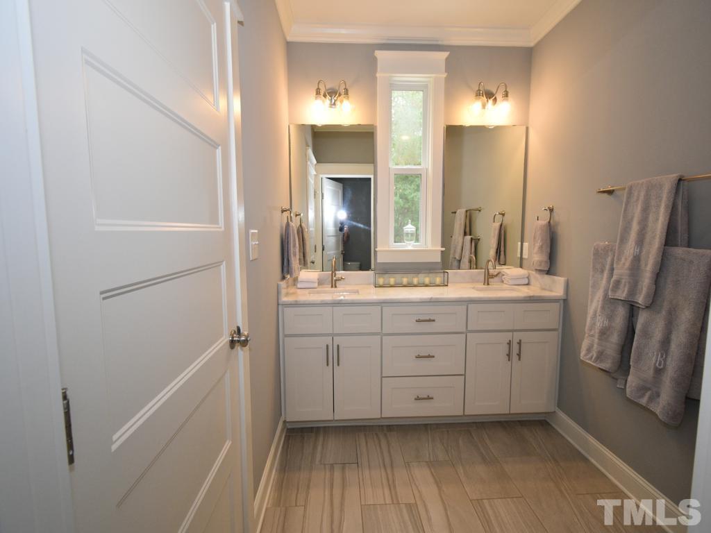 607 Morreene Road Durham, NC 27705 - Photo 34 of 48 a bathroom with a double vanity sink a mirror and a shower