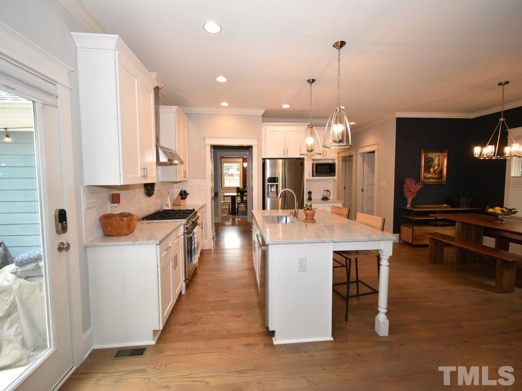607 Morreene Road Durham, NC 27705 - Photo 7 of 48 a large white kitchen with lots of counter space and chandelier