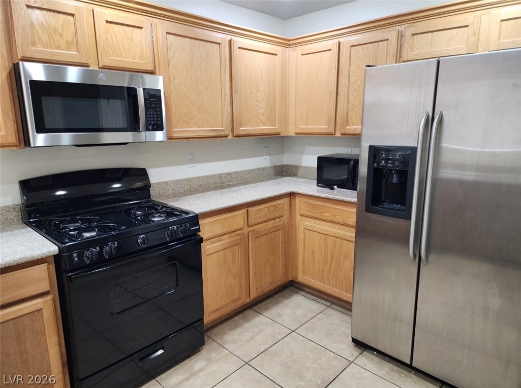11901 Fairfax Ridge Street Las Vegas, NV 89183 - Photo 11 of 46 Kitchen featuring black appliances, light countertops, light tile patterned floors, and light brown cabinets