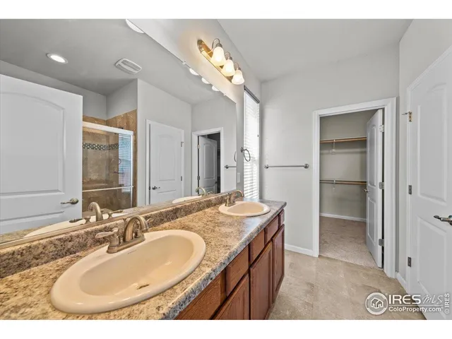 a bathroom with a granite countertop sink a mirror and shower