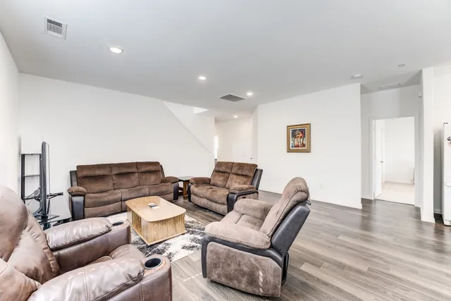 a kitchen with stainless steel appliances granite countertop a refrigerator a stove a sink a dining table and chairs with wooden floor