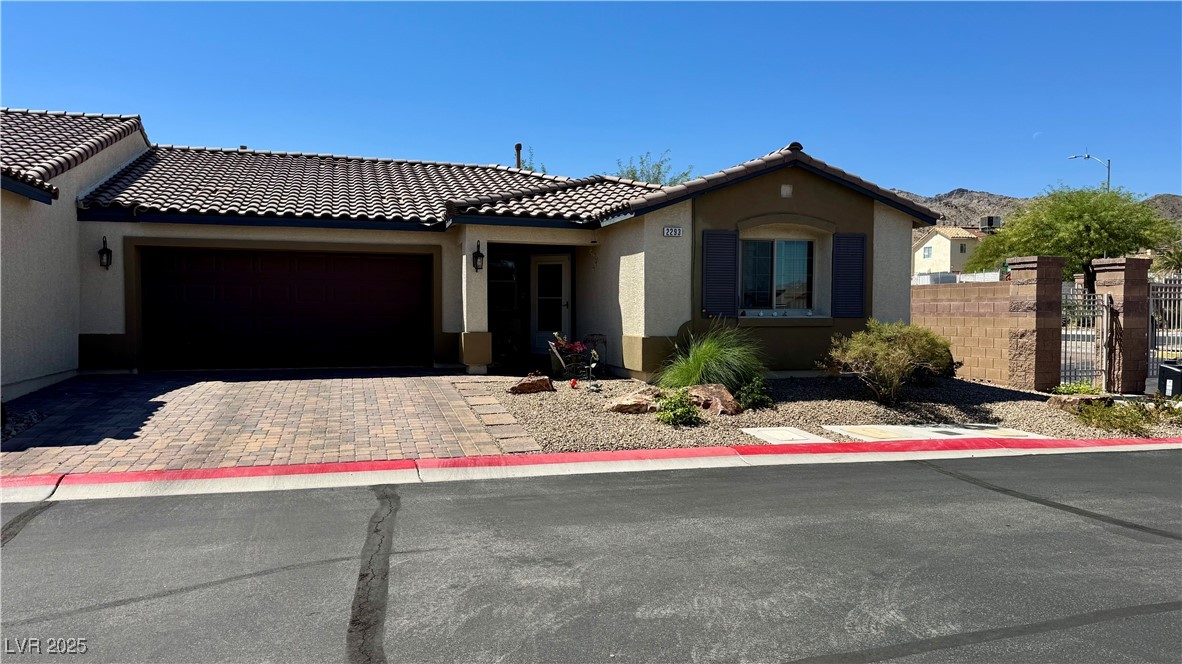 2293 Chandler Ranch Place Laughlin, NV 89029 - Photo 2 of 23 View of front facade featuring stucco siding, decorative driveway, a tiled roof, and a garage