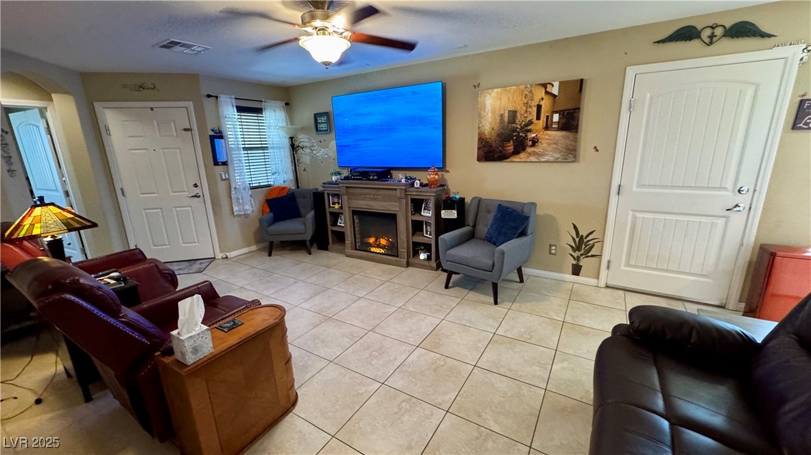 2293 Chandler Ranch Place Laughlin, NV 89029 - Photo 7 of 23 Tiled living room featuring ceiling fan, a warm lit fireplace, and arched walkways