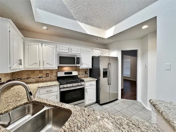 a kitchen with stainless steel appliances granite countertop a refrigerator sink and stove