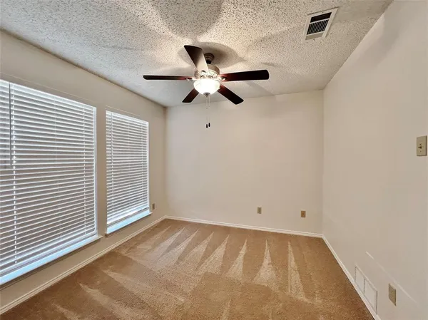 an empty room with chandelier fan and windows