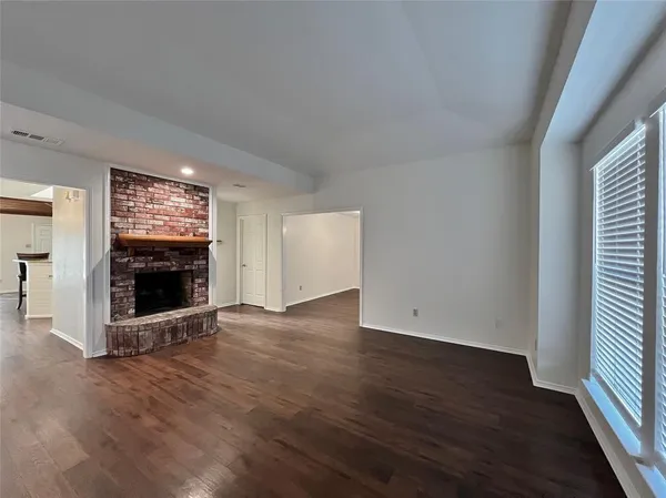 an empty room with wooden floor and fireplace