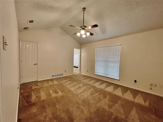 a view of an empty room with chandelier fan and window