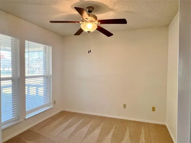 an empty room with a window and a ceiling fan