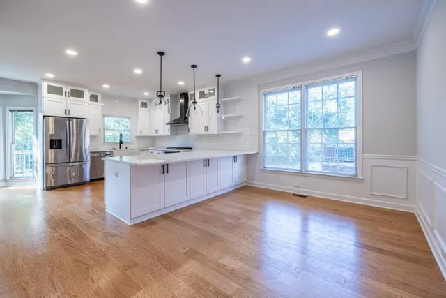 a large kitchen with stainless steel appliances a large counter top a stove a refrigerator a sink and a large window