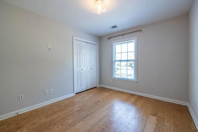 a view of an empty room with a window and wooden floor