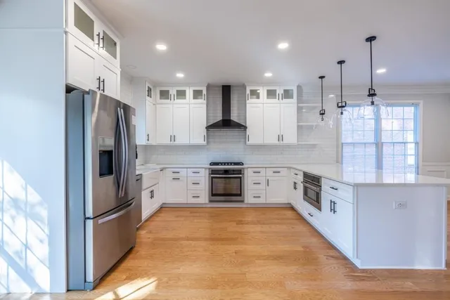 a large kitchen with stainless steel appliances kitchen island a large counter top and a wooden floors