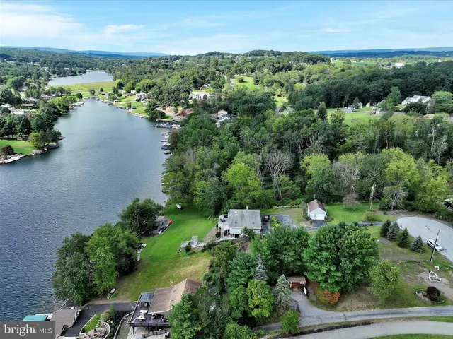 an aerial view of a residential houses with outdoor space and trees all around