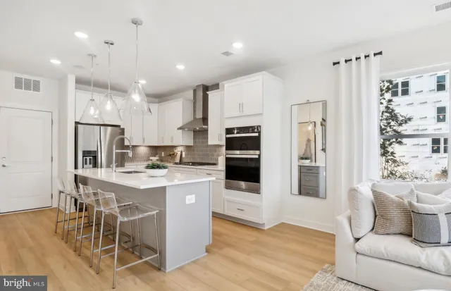 a living room with stainless steel appliances furniture and a kitchen view