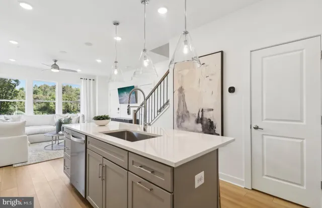 a kitchen with stainless steel appliances kitchen island granite countertop a refrigerator a stove a sink and white cabinets with wooden floor