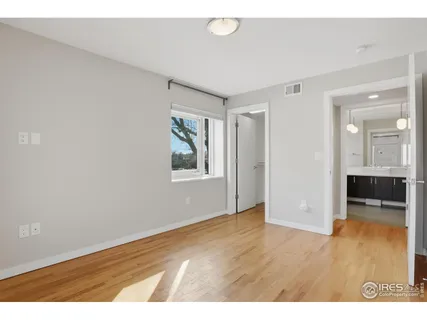 a view of an empty room with window and wooden floor