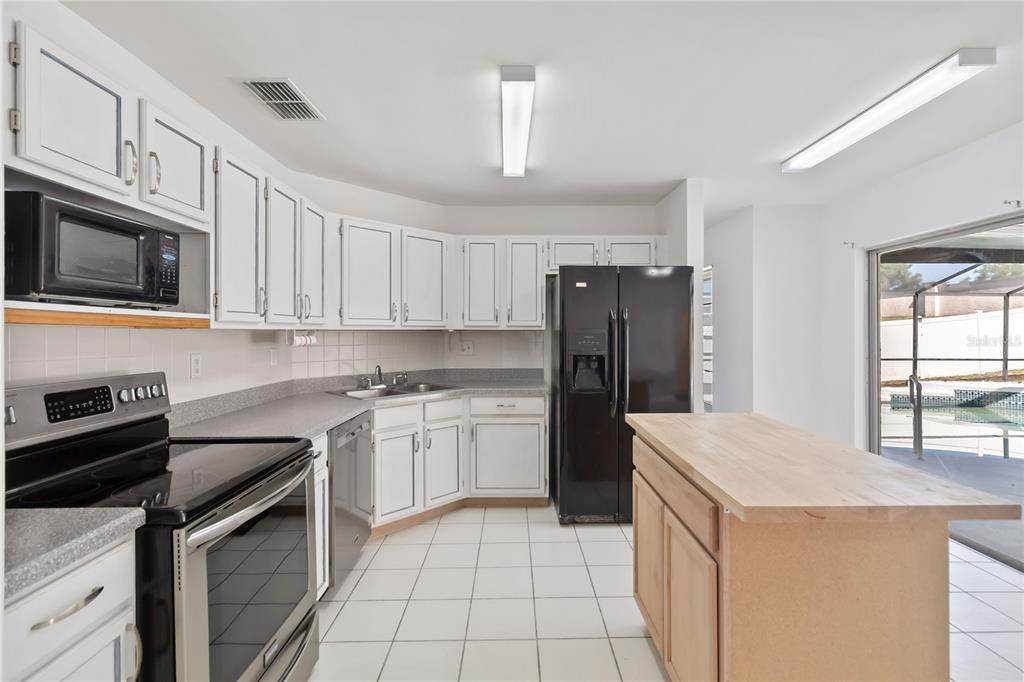 7771 Indian Ridge Trail North Kissimmee, FL 34747 - Photo 13 of 51 a kitchen with stainless steel appliances granite countertop a refrigerator stove microwave and sink