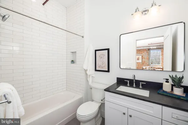 a bathroom with a granite countertop sink a toilet a mirror and shower
