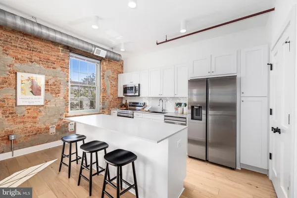 a kitchen with stainless steel appliances a refrigerator a stove a dining table and chairs
