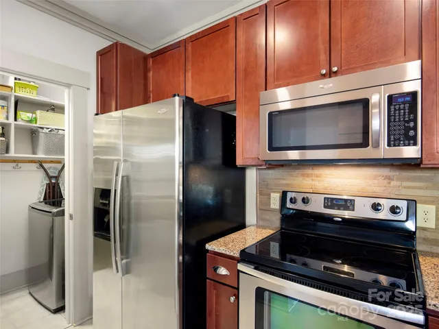 a kitchen with granite countertop a refrigerator stove and microwave