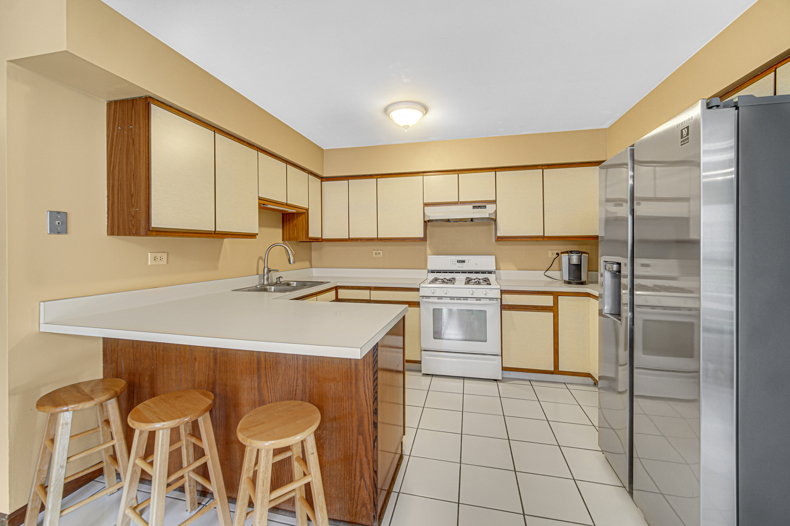 316 Morningside Drive, Unit A Bloomingdale, IL 60108 - Photo 10 of 35 a kitchen with a sink a stove a refrigerator and white cabinets