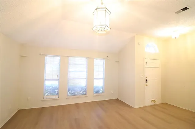 an empty room with windows and ceiling fan