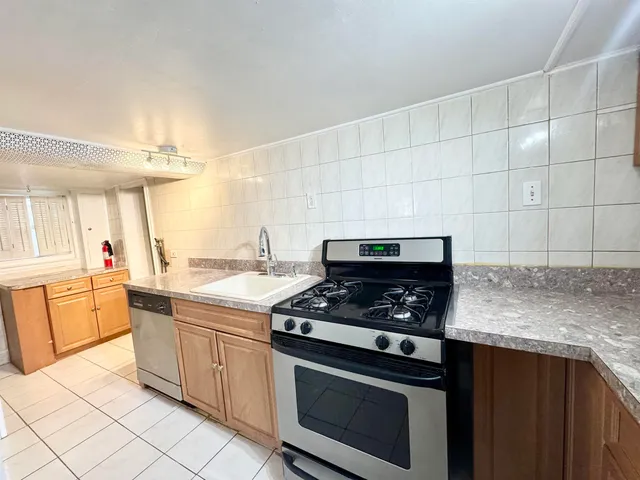 a kitchen with granite countertop a stove sink and cabinets