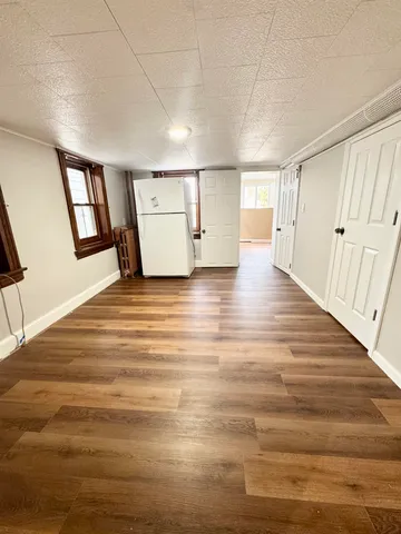 a view of an empty room with window and wooden floor