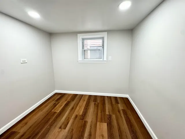 a view of a room with wooden floor and small window
