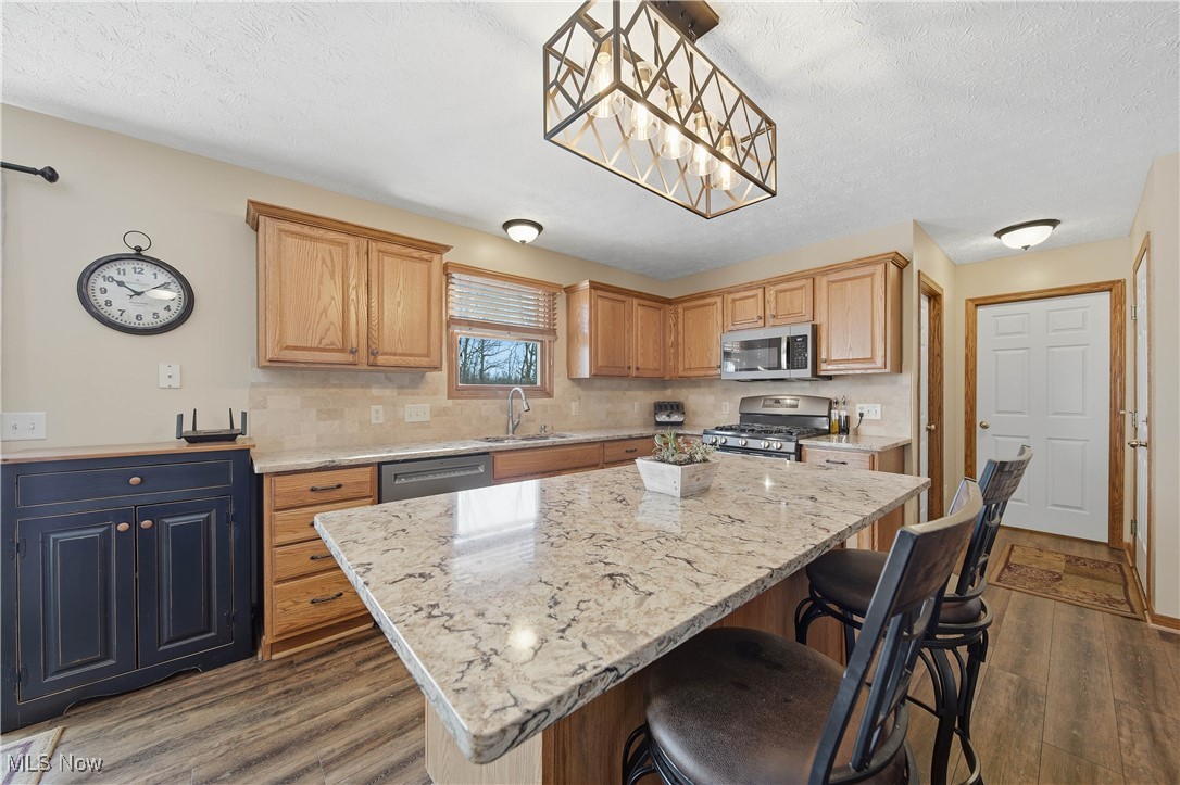 2132 Summerchase Road Northeast Canton, OH 44721 - Photo 8 of 49 Kitchen with hanging light fixtures, appliances with stainless steel finishes, dark wood finished floors, light stone countertops, and a textured ceiling