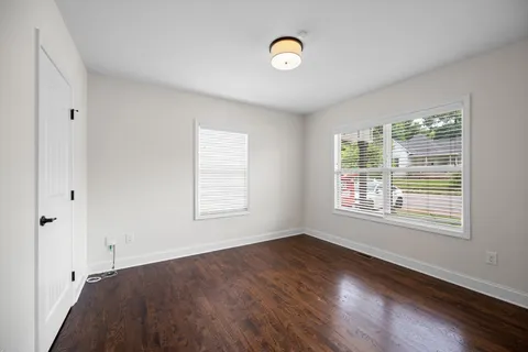 a view of an empty room with a window and wooden floor
