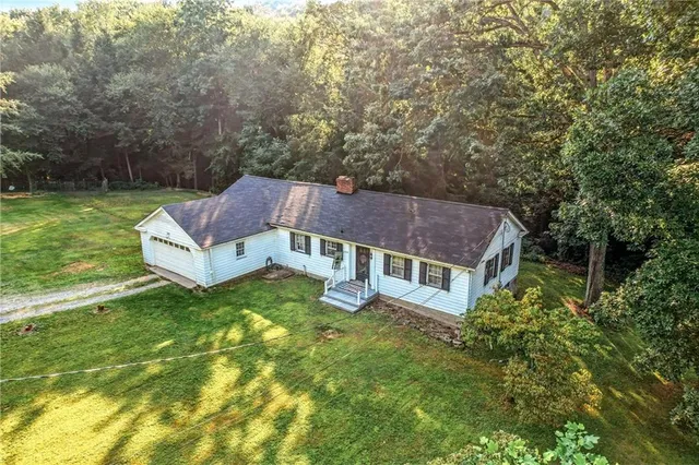 a view of a house with a big yard plants and large trees