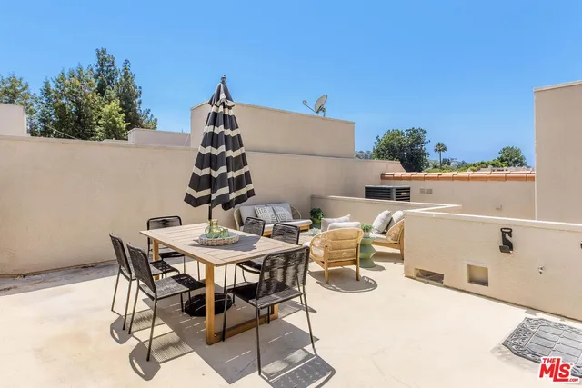 a roof deck with table and chairs and potted plants