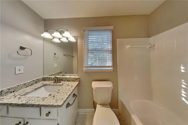 a bathroom with a granite countertop sink a toilet and shower