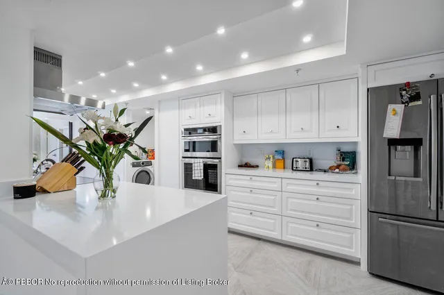 a kitchen with stainless steel appliances a sink a potted plant and cabinets