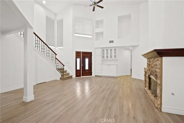 a view of empty room with wooden floor and kitchen view