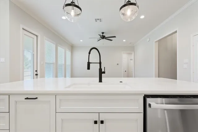 a view with granite countertop a sink and chandelier
