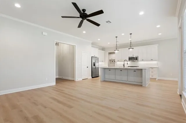 a large kitchen with stainless steel appliances kitchen island a large counter top and a chandelier