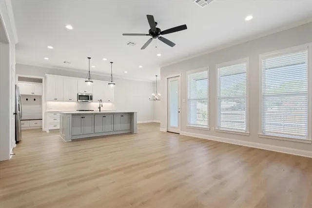 a view of an empty room with a kitchen and a window